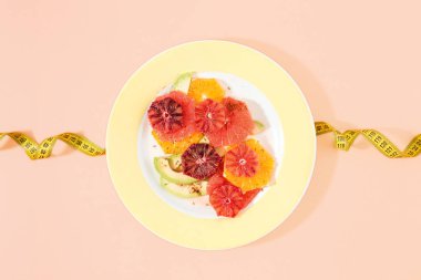 Portakal, greyfurt ve avokado teyp ölçme ile pembe arka plan üzerinde sağlıklı diyet meyve salatası yaptı. Üstten görünüm, düz yatıyordu. Diyet ve sağlıklı gıda kavramı