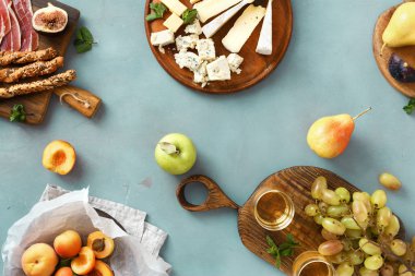 Üstten görünüm düz çeşitli şarap atıştırmalıklar yatıyordu: üzüm, şeftali, kayısı, armut, elma, jamon, sert peynir, brie peyniri ve Rokfor peyniri cam mavi taş zemin üzerine beyaz şarap