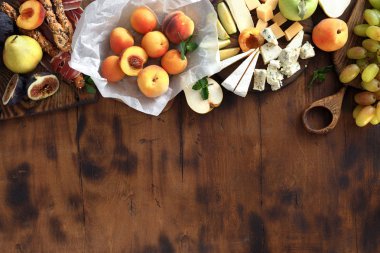 Meze tablo kenarlığı olan şarap için. Çeşitli aperatifler şarap: üzüm, şeftali, kayısı, armut, elma, jamon, sert peynir, brie peyniri ve Rokfor peyniri ahşap masa üstten görünüm üzerinde düz lay