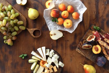 Şarap için meze tablo. Çeşitli aperatifler şarap: üzüm, şeftali, kayısı, armut, elma, jamon, sert peynir, brie peyniri ve Rokfor peyniri ahşap masa üstten görünüm üzerinde düz lay
