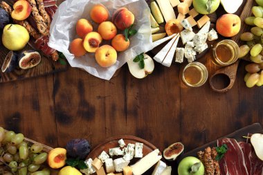 Meze şarap cam beyaz şarap ile bir masa. Çeşitli şarap atıştırmalıklar çerçevesinde: üzüm, şeftali, kayısı, armut, elma, jamon, sert peynir, brie peyniri ve Rokfor peyniri ahşap masa üstten görünüm üzerinde düz lay