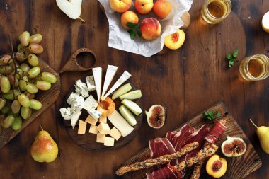 Çeşitli aperatifler şarap: üzüm, şeftali, kayısı, armut, elma, jamon, sert peynir, brie peyniri ve Rokfor peyniri cam beyaz şarap en iyi manzaralı ahşap masa üzerinde düz lay