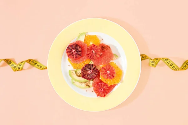 健康的な食事フルーツ サラダはオレンジ グレープ フルーツとアボカド 測定テープとピンクの背景から成っています トップ ビュー フラット横たわっていた 健康と栄養食品のコンセプト — ストック写真