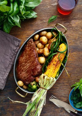 Sığır eti biftek tavada kızarmış Mısır, patates ve kırmızı şarap, üstten görünüm ile ahşap tabloda yeşil fasulye ile hizmet