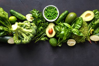 Çiğ sağlıklı gıda sebze yeme temiz: salatalık, yonca, kabak, ıspanak, fesleğen, yeşil bezelye, dereotu, maydanoz, avokado, brokoli, kireç karanlık taş zemin, üstten görünüm