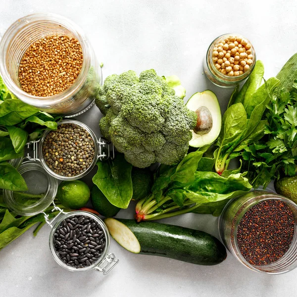 Healthy food, clean eating, selection source of protein for vegetarians: cucumber, lucerne, zucchini, spinach, basil, avocado, lime buckwheat, black beans, black quinoa, chickpeas, green lentils on gray concrete background, top view. — Stock Image Healthy Food Clean Eating Selection Source Protein Vegetarians Cucumber Lucerne Royalty Free Stock Images