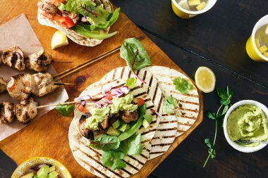 Üstten görünüm tacos ızgara tavuk koyu arka plan üzerinde sebze salsa, guacamole sos ile