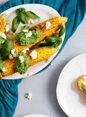 Tatlı Mısır gri arka plan, üstten görünüm üzerinde plaka üzerinde pesto sos ve beyaz peynir ile kızarmış