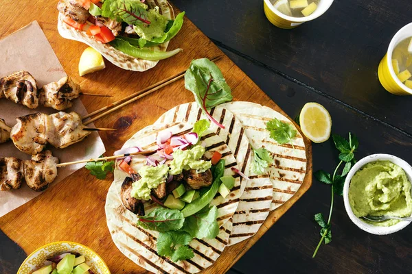 Üstten görünüm tacos ızgara tavuk koyu arka plan üzerinde sebze salsa, guacamole sos ile
