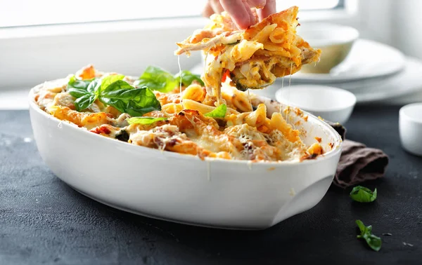 Comfort food concept. Baked pasta with chicken, ham and mozzarella and parmesan cheese with pumpkin sauce