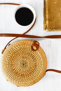 Üstten görünüm bambu çanta, kitap ve fincan beyaz ahşap arka plan üzerinde kahve. Yaz modası, tatil