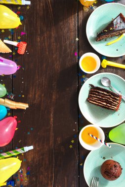 Üstten görünüm Çocuk Doğum günü tablo kavramı. Çerçeve çikolatalı kek ve dekorasyon partisi düz kahverengi ahşap zemin üzerinde yatıyordu