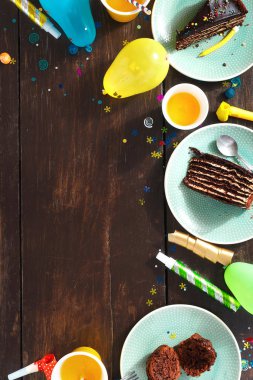 Çerçeve çikolatalı kek ve dekorasyon partisi düz kahverengi ahşap zemin üzerinde yatıyordu. Üstten görünüm Çocuk Doğum günü tablo kavramı