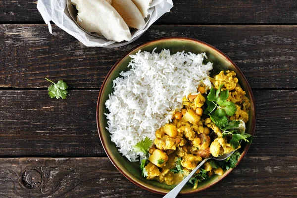 Karnabahar baharatlı köri pirinç ve naan ekmek üzerinde koyu ahşap arka plan kopya alanı üstten görünüm