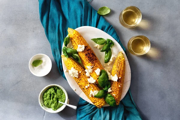 Kavrulmuş mısır gri beton zemin üstten görünüm bir tabakta servis beyaz peynir ve pesto sos ile