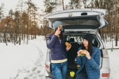 Freundinnen in Winterkleidung an einem verschneiten Tag im Winterwald im Auto beim Reden und Kaffeetrinken