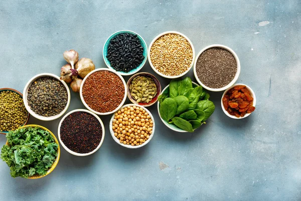 Super food or vegetarian food concept. Seeds, cereals, beans, vegetables, herbs for healthy cooking on blue stone background top view with copy space