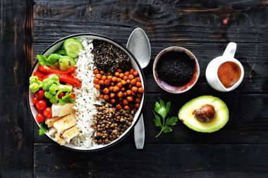 Buda kase: pirinç, baharatlı nohut, siyah quinoa, sebze ve koyu ahşap arka plan üzerinde tavuk fileto