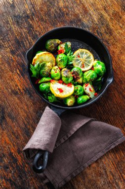 Fried Brüksel lahanası ve kabak kızartma tavası gri beton zemin üzerine servis