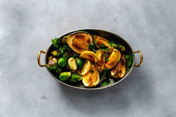 Fried Brüksel lahanası ve kabak kızartma tavası gri beton zemin üzerine servis
