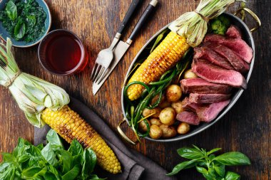 Üstten görünüm dilim Dana biftek tavada kızarmış Mısır, patates ve yeşil fasulye ahşap masa üzerinde hizmet