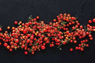 Küçük kiraz domates siyah arka plan üzerine yığını 