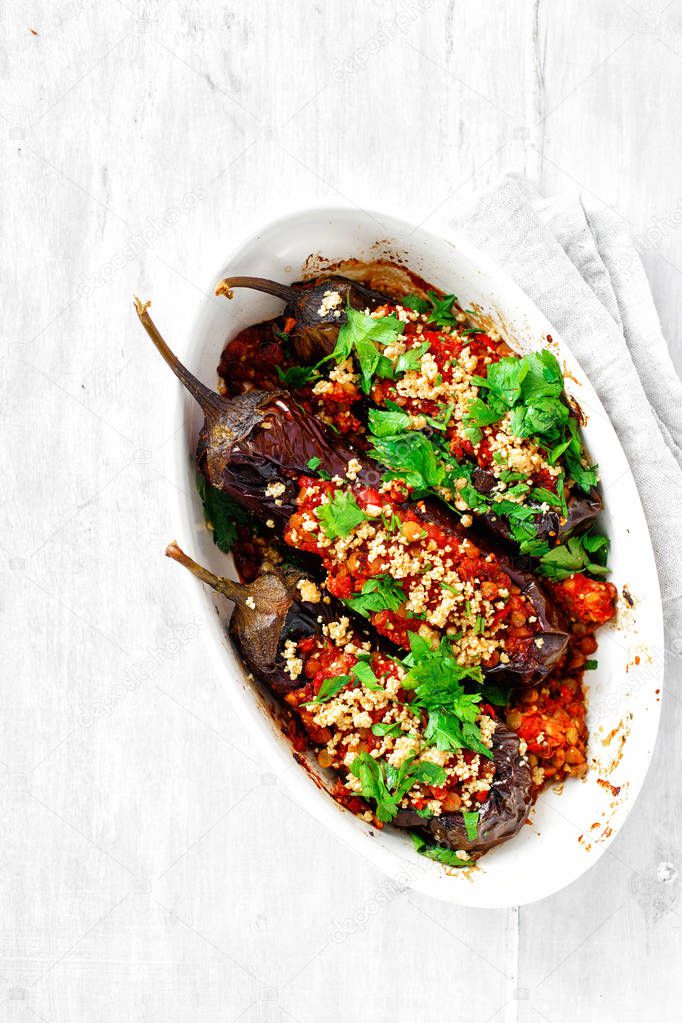 Stuffed eggplants with green lentils, tomatoes and nuts on white table
