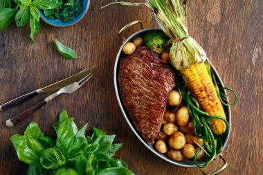 Sığır eti biftek tavada kızarmış Mısır, patates ve yeşil fasulye ahşap masa üzerinde hizmet