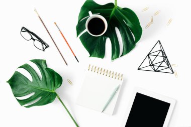 Tabletli, aksesuarlı ve canavar yapraklı modern ofis masası kadınsı çalışma alanı.