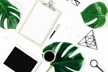 Tabletli, aksesuarlı ve canavar yapraklı modern ofis masası kadınsı çalışma alanı.