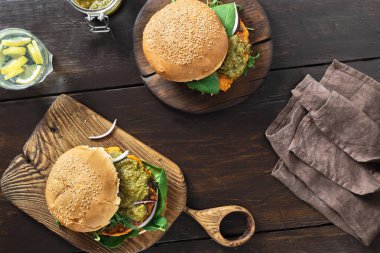 Sağlıklı vejetaryen gıda kavramı. Üstten görünüm vejetaryen burger kabak pirzola, ıspanak, roka ve vejetaryen pesto sos ahşap masa tabakta servis