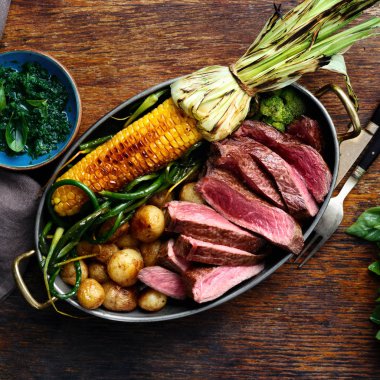 Dilim Dana biftek tavada kızarmış Mısır, patates ve fesleğen sos, üstten görünüm ahşap zemin üzerine yeşil fasulye ile servis