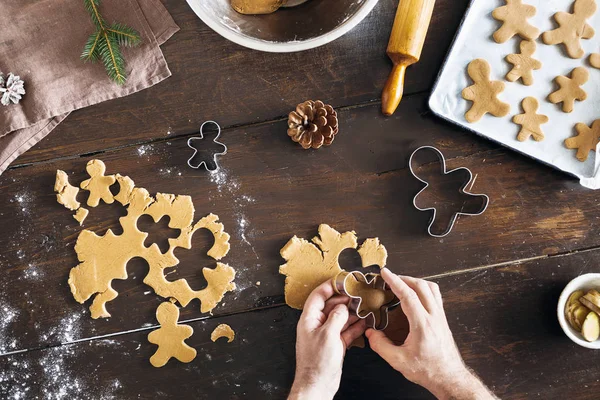 Christmas food concept. Man cooking gingerbread man cookies in Christmas on wooden table top view. Xmas dessert