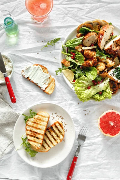 Lunch food bowl of fresh salad with hicken steak and fried cauliflower on white background with grapefruit fresh and toasts top view. Healthy food concept