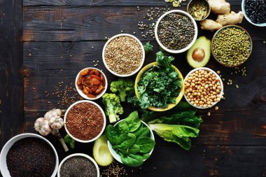 Superfoods koyu ahşap masa üzerinde ayarlayın. Yaprakları, tahıllar ve üstten görünüm tohum. Sağlıklı vejetaryen yemek