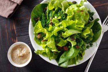 Üstten görünüm plaka yeşil salata koyu ahşap masa üzerinde. Diyet ve sağlıklı gıda kavramı