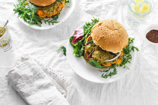 Vegetarian burgers made of pumpkin cutlet, spinach, arugula and pesto sauce served on plates