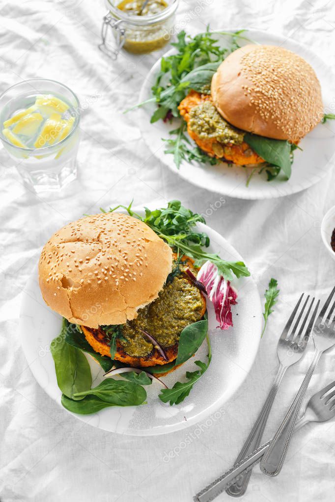 Vegetarian burgers made of pumpkin cutlet, spinach, arugula and pesto sauce served on plates