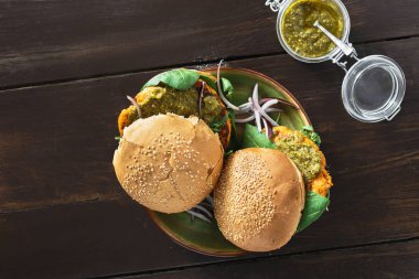 Ahşap masa tabağa vejetaryen burger kabak pirzola, ıspanak, roka ve vejetaryen pesto sos ile servis