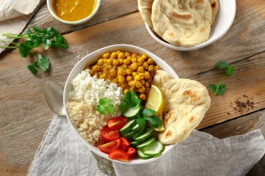 Ahşap masa üstten görünüm naan ekmek ile Vegan Buda kase. Sağlıklı vejetaryen gıda kavramı