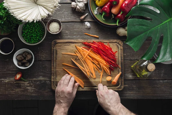 Ev mutfağında erkek eller vejetaryen Tay erişte koyu ahşap masa üstten görünüm üzerinde hazırlamak.