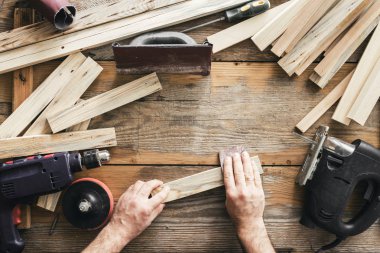 Marangoz marangozluk atölyesinde çalışıyor. Adam el ile zımparalama tahta üstten görünüm