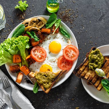 Kızarmış yumurta sebze, mantar ve kızarmış ekmek koyu arka plan üzerinde 