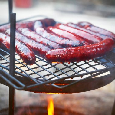 Sulu ızgara sosis ızgara duman ve alevler ile. Barbekü yaz arka plan