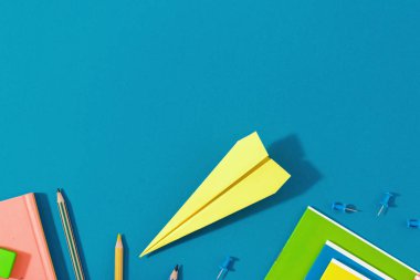 Üstten görünüm Okul arka plan. Okul kavramı kağıt uçak ile başa yat ve mavi arka plan üzerinde okul malzemeleri