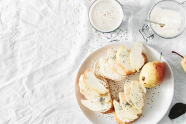 Krem peynirli sandviç, armut ve yulaf sütü kopya alanı, üstten görünüm beyaz zemin üzerine. Sağlıklı kahvaltı veya Aperatif