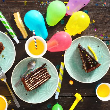 Çikolatalı kek ve dekorasyon parti kahverengi ahşap masa düz üzerinde yatıyordu. Üstten görünüm Çocuk Doğum günü tablo şenlikli gıda ile