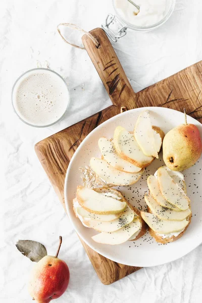 クリーム チーズのサンドイッチ 白い背景に 上面に梨とエンバク ミルク 健康的な朝食や木の板でおやつ — ストック写真