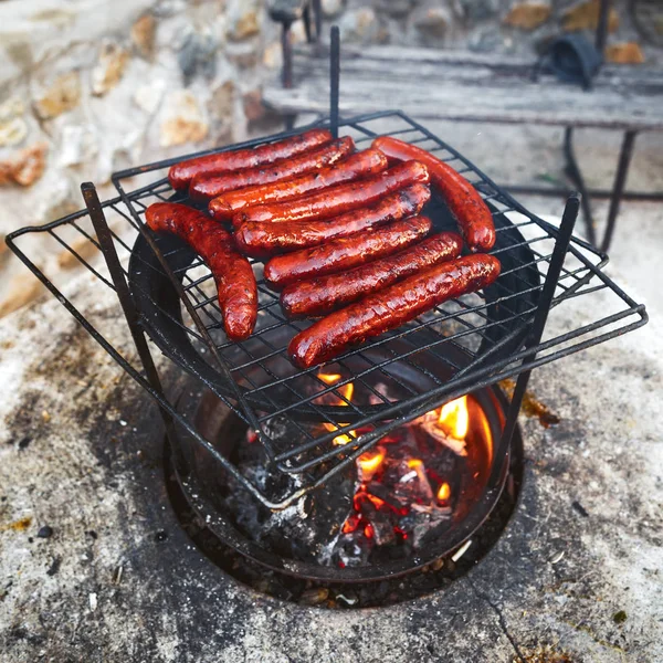 Grilled sausages on the grill with flames. BBQ background