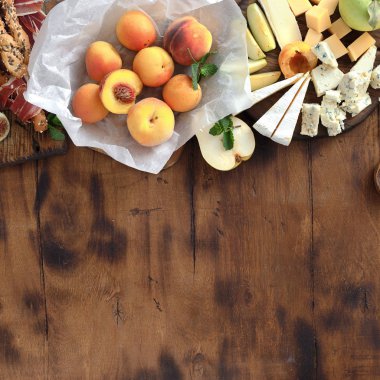 Meze tablo kenarlığı olan şarap için. Çeşitli aperatifler şarap: üzüm, şeftali, kayısı, armut, elma, jamon, sert peynir, brie peyniri ve Rokfor peyniri ahşap masa üstten görünüm üzerinde düz lay